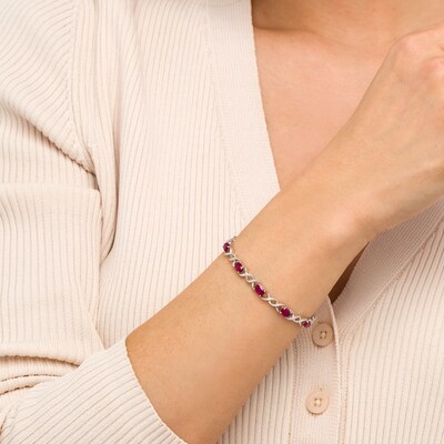 Oval Lab-Created Ruby and 0.18 CT. T.W. Diamond Infinity Ribbon Link Line Bracelet in Sterling Silver – 7.5"